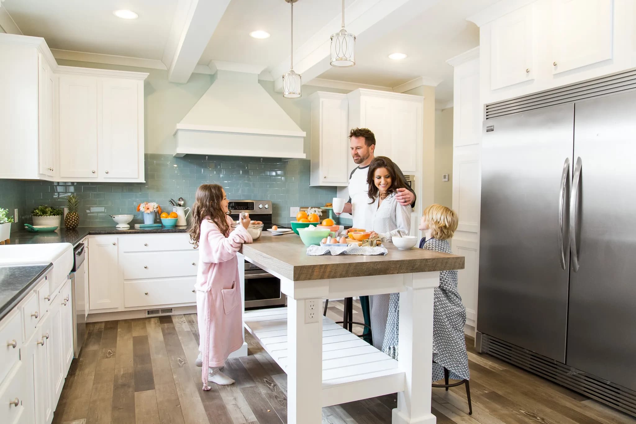 Family stands in their new construction open floor plan kitchen making breakfast.