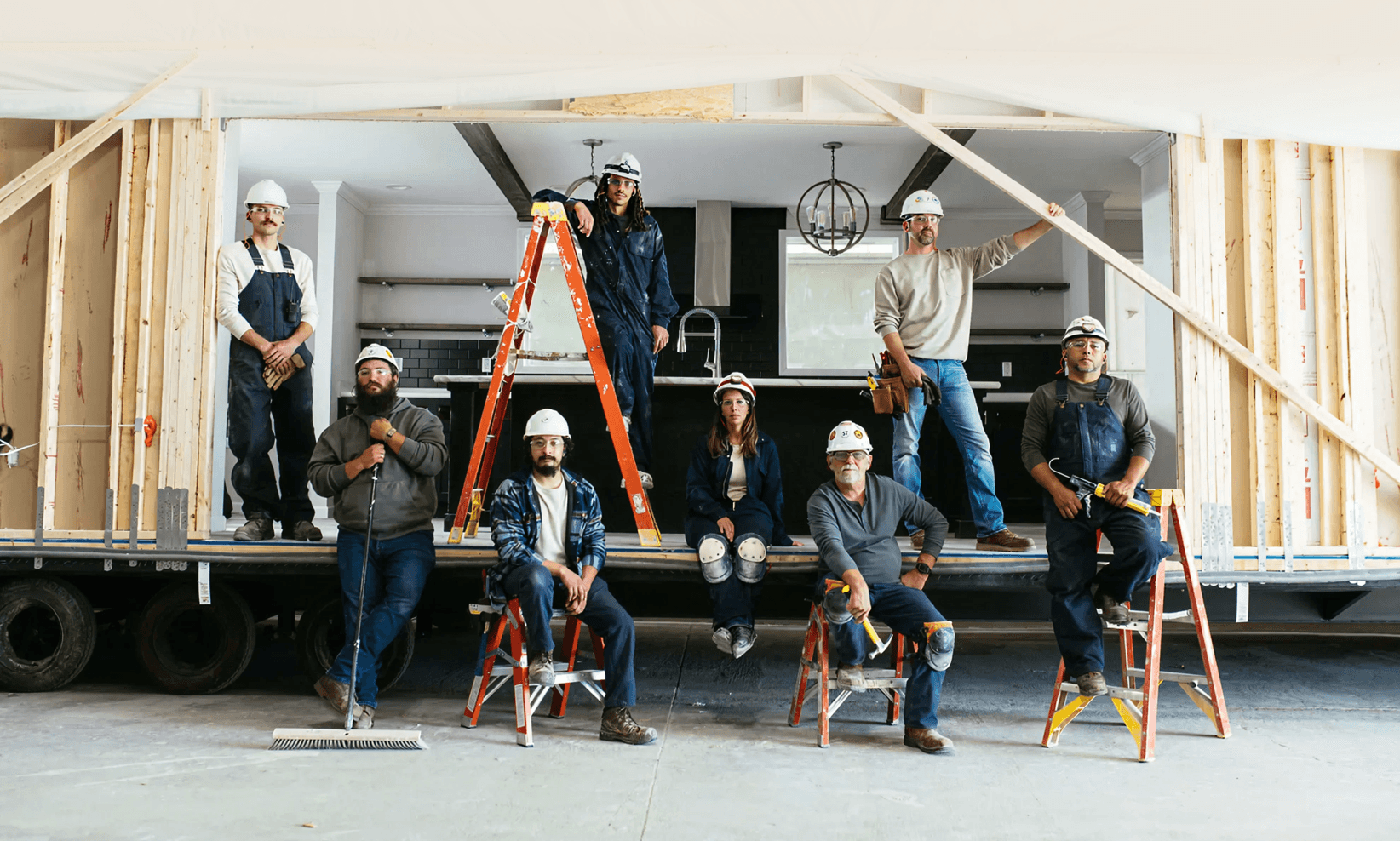 Home building and construction crew members next to a modern manufactured home by Clayton.