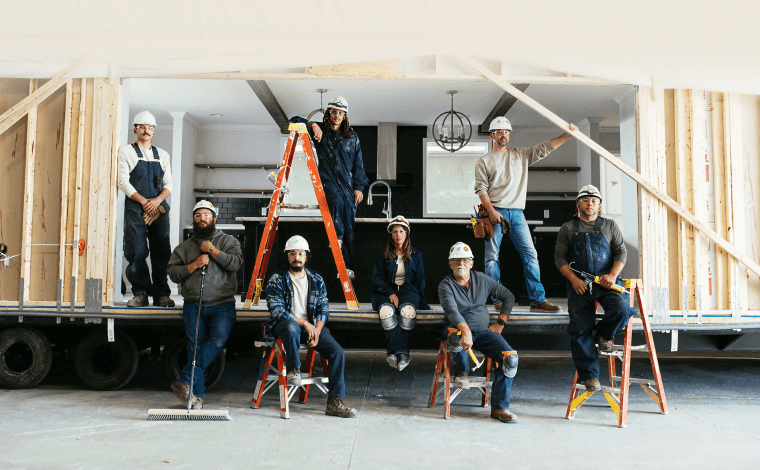 Home building and construction crew members next to a modern manufactured home by Clayton.