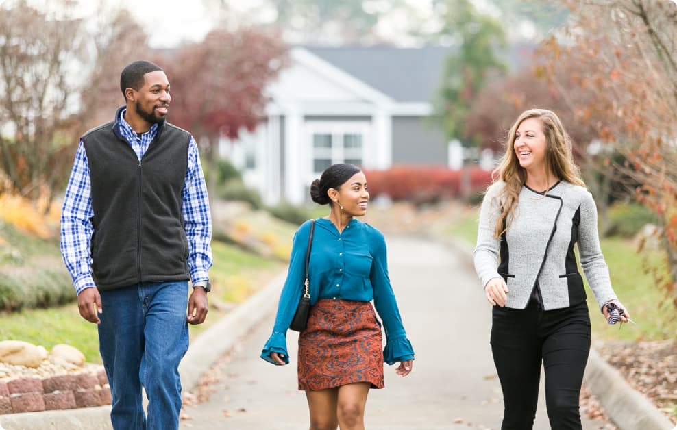 A couple walks with a home consultant at a home center location while shopping and touring new construction homes.