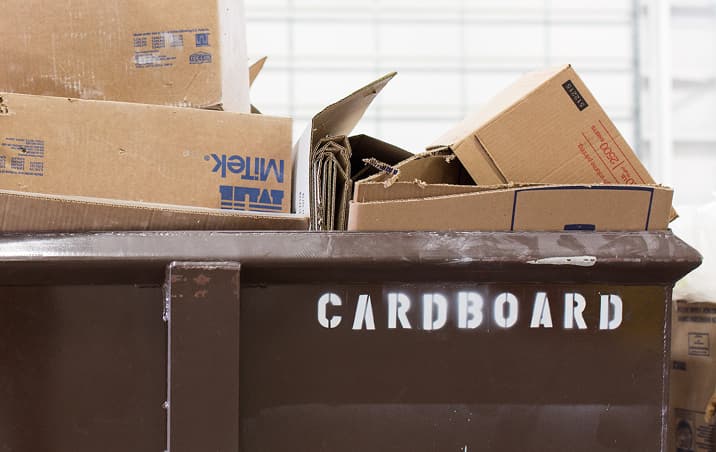 Cardboard boxes are in a recycling bin to be processed as waste is reduced in building facilities.
